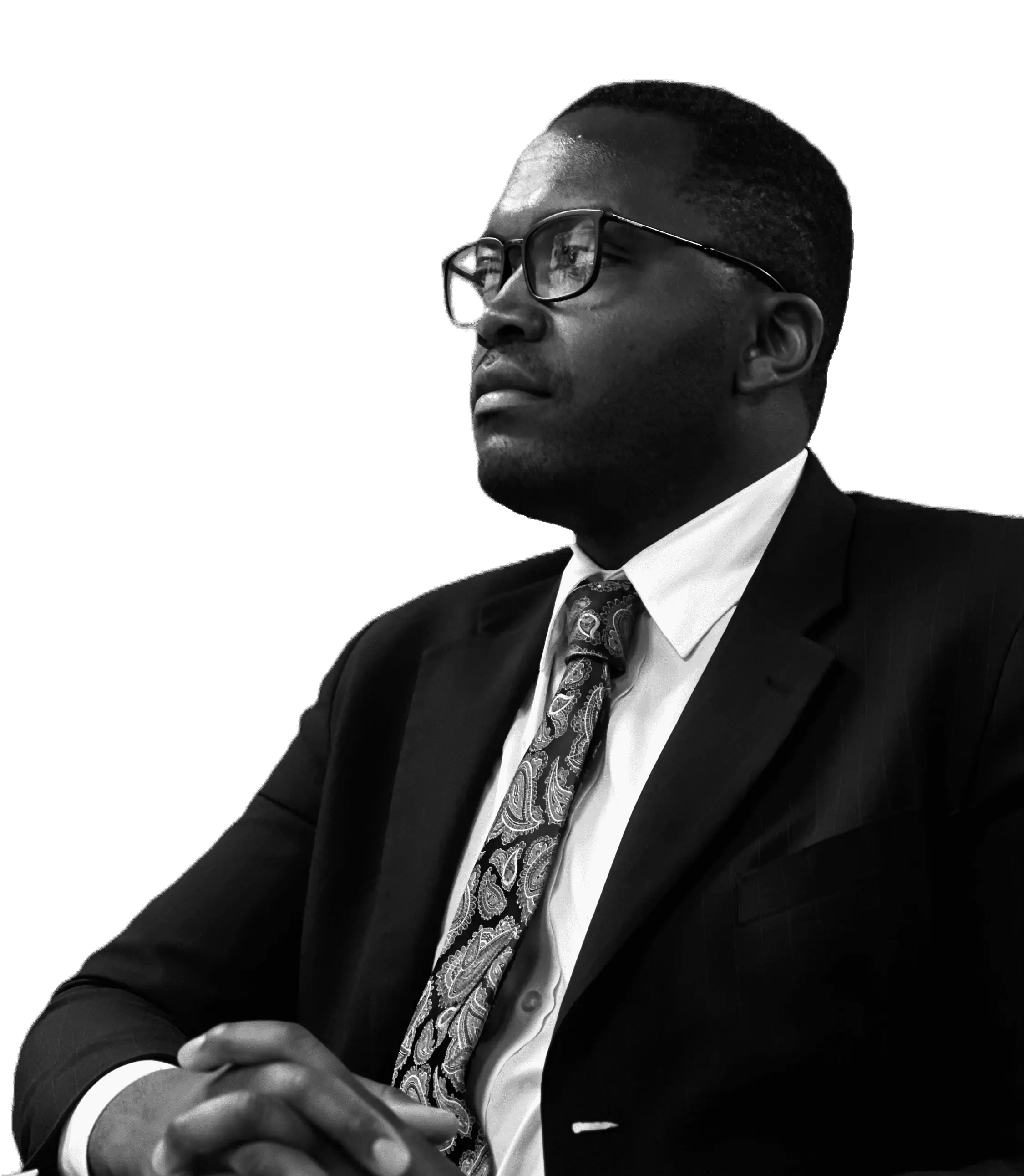 Black and white photo of Nicholas Webaza wearing a suit and tie, looking with conviction upon his next legal project.